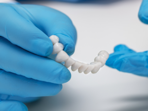 Dentist holding a custom dental bridge for tooth replacement