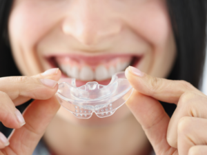 Smiling patient holding a clear mouth guard
